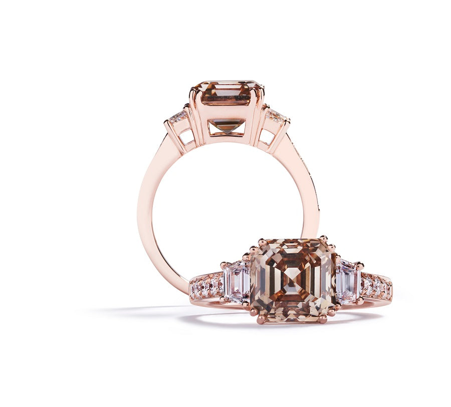 3-stens ring i 18 kt. rosaguld prydet med en 4,01 ct. Asscher-cut Natural Fancy Yellow Brown/VS2 diamant flankeret af to trapezslebne River/VVS diamanter, i alt 0,50 ct. samt 10 Top Wesselton/VVS-VS brillanter, i alt 0,25 ct.